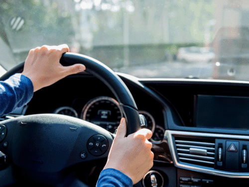 Person driving with both hands on steering wheel