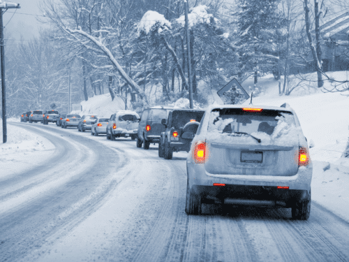 Line of cars on snowy, icy road.